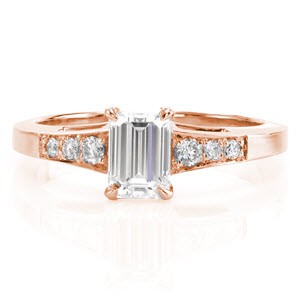 This elegant ring uses the smooth, straight lines of the band to compliment the straight lines of the 0.80 carat emerald cut center diamond. The three round brilliant cut diamonds on either side of the center stone are a beautiful contrast. These side stone graduate in size to match the slight flare of the band.