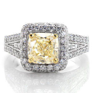 A magnificent halo design enveloped with micro pavé, this ring glimmers and shines from every angle. The center is a 1.50 carat fancy yellow cushion cut diamond set with an accent of yellow gold prongs. Channel set baguettes rest in the middle of the micro pavé. The design is framed with milgrain edges.