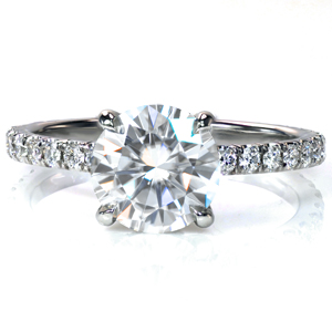 This classic look is exquisitely made in platinum with a hand cut micro pavé band. It currently features a 1.25 carat round center diamond with diamonds in the sides of the setting. The sparkling side stones are simply enthralling and make the design look stunning. This is definitely a head turner! 