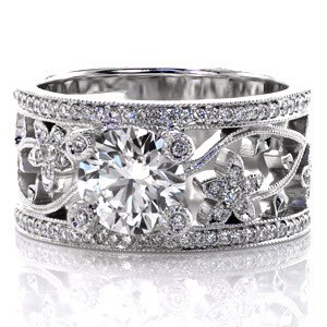 A magnificent piece that is all sparkle, Design 2297 features a 1.25 carat round center stone. The unique wide band features a floral pattern and lots of micro pave side stones; you'll be mesmerized by them. Each of the prongs even has a single small diamond set into it surrounded by milgrain! 