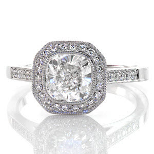 This beautiful halo ring features a 1.20 carat cushion cut center in a full bezel setting. There is micro pavé detailing on the halo, band, and even under the setting of the center diamond! This touch really adds to this splendid design. The look is completed with fine, milgrain on all the edges. 