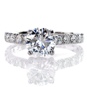 Graceful platinum lines unite in our Adora Design. U-Cut prongs hand-formed by our jewelers, securely fashion diamonds along the length of the band.  Up-swept shoulders join an alluring four prong basket which displays a 1.20 carat round brilliant cut center diamond that is absolutely breathtaking!