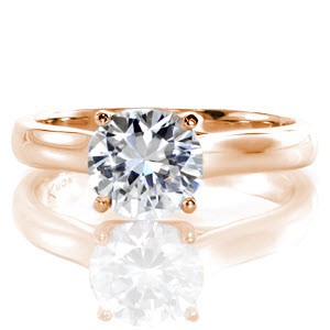 Camilla is a unique take on the classic solitaire design. A four prong crown delicately holds the 1.00 carat round brilliant center diamond. In the side view, the prongs delightfully graze one another perfectly framing the diamond before merging into the shank. 
