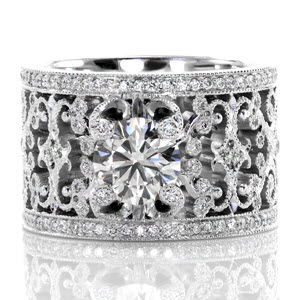 The captivating pierced pattern is adorned with micro pavé diamonds and milgrain detail. The 1.00 carat round center stone is delicately held by four spiral prongs extending from the design which are tipped with diamonds. Two rows of bead set diamonds border the design to add exquisite brilliance.