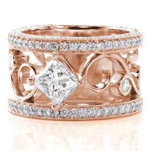 Our Kristin Marie design features a .70 carat princess cut center stone held in a four prong crown. The pierced filigree curl detail holds two diamonds within exquisite wire work. The design is embellished with two rows of micro pavé diamonds that continue along the side face.