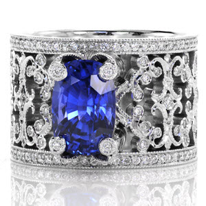 Intricate pierced scrolls created in 14k white gold and adorned with bead set diamonds. For Design 2352, the natural 3.50 carat cushion cut blue sapphire is embraced with four regal, diamond capped prongs. Hand applied milgrain finishes our Knox Signature heirloom band.