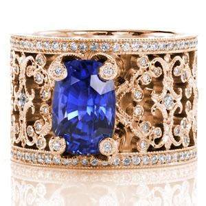 Intricate pierced scrolls created in 14k white gold and adorned with bead set diamonds. For Design 2352, the natural 3.50 carat cushion cut blue sapphire is embraced with four regal, diamond capped prongs. Hand applied milgrain finishes our Knox Signature heirloom band.