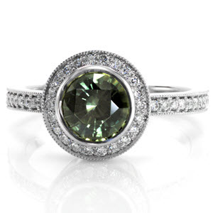 The forest green hue of the 1.50 carat gemstone gives the Ashley design a nature-like quality. Bead set diamonds encircle the round sapphire to enhance the deep green of the center gem. Similar micro pavé diamonds line the band for a completed look.