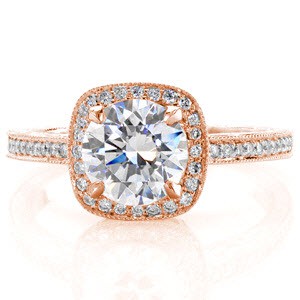 The Aurora design displays heirloom quality elements of hand wrought filigree on the sides of the squared, micro pavé bead set diamond halo. The alluring hand engraving cascades down both ring faces and the 1.25 carat round brilliant cut center diamond is secured by four beveled prongs. 