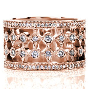 Royale is a wide band with pierced elements that create a unique and beautiful pattern. The design features rows of alternating star-bursts and circles finished with glimmering diamonds. The band is framed with rows of micro pavé diamonds that are embellished with a milgrain beaded edge.