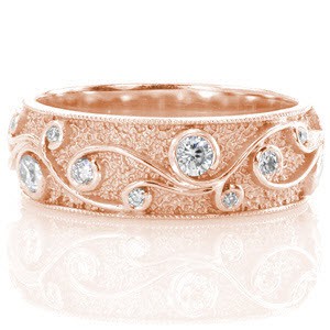Rose gold wedding ring with filigree curls, stippled background and round cut diamonds.