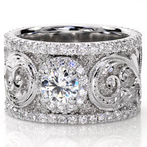 Calabria is a stunning work of art. A 0.50 carat center stone is accented with a micro pavé halo. The scroll work along the wide band is magnificent with hand engraved detail and faceted stipple background that captures the light. Two rows of micro pavé diamonds frame the picturesque design. 