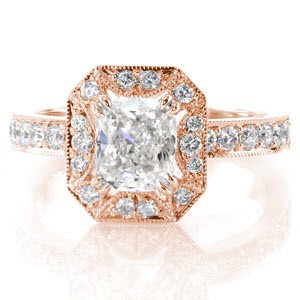 This glamorous design is shown with a 1.00 carat cushion cut center diamond in a claw prong setting. The halo has a unique starburst pattern cut-out around the center stone. The top of the band and the halo are exquisitely adorned with micro pavé and edged in milgrain for a refined finish.