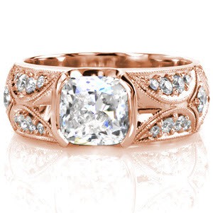 A mesmerizing design of dazzling star bursts accented with micro pavé on a wide band. Each section is edged in milgrain for a refined finish leading in to the 1.50 carat cushion cut center diamond. The center stone is set with a graceful half bezel which preserves the flow of the band's pattern.