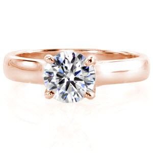 This classic solitaire design features a sleek wide band and a 1.00 carat round brilliant center diamond. The side profile reveals a beautiful row of micro pavé surprise diamonds at the base of each side of the center stone. The prongs extend and curve down to meet the bridge of the band. 