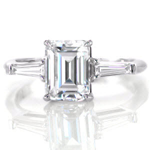 Ann Arbor classic custom engagement ring on a slim polished band with an emerald cut diamond center bordered on either side by a tapering banquette diamond.