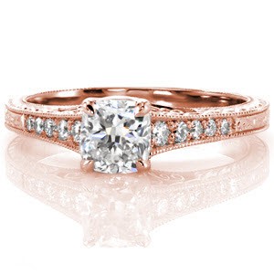 This pleasing vintage-inspired design displays a 0.80 carat cushion cut center diamond set in a four prong style crown. The cathedral style design gracefully rises to meet the top of the setting. The band is adorned with micro pavé tapering diamonds, hand engraving, and filigree. 