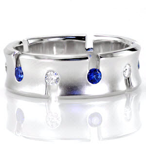 This alluring take on an eternity band features alternating rich blue sapphires and white diamonds. Each stone is fashioned along the center of the concave band for a decorative appeal. The wide band is given a matte finish in the middle with high polished edges for a stunning contrast.