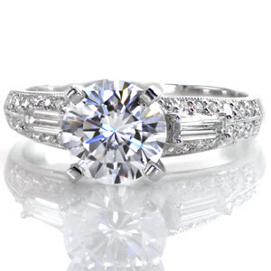 A magnificent piece with lots of glimmering diamonds, the Calista Design features a 1.70 carat round center stone. To either side there is an elegant baguette surrounded by two rows of exquisite micro pavé. The edges are finished with milgrain to provide a tailored, defined look to the ring.