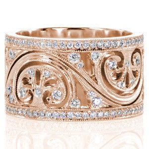 This vintage inspired wide band features a flowing pattern with pierced elements and art deco inspired fan shapes. There are bezel set diamonds within the center design and two rows of micro pavé diamonds framing the pattern. The edges of each section are detailed with milgrain texture for added definition.