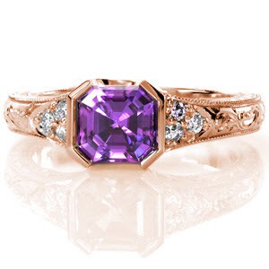 The striking 1.30 carat asscher cut natural purple sapphire is set perfectly within Design 2492. The half bezel design is complimented by round diamond side stones. The hand engraved band displays fine milgrain edges. Four pockets within the 14k white gold band frame intricate hand wrought filigree scrolls.