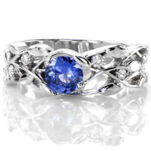 The Sapphire Allamanda creates a labyrinth of trailing vines and petals. In 14k white gold, the open pockets nest a natural 0.50 carat round cut sapphire of deep blue. Rare petal prongs join the center stone into the design and round cut diamonds add the right touch of sparkle to the band.