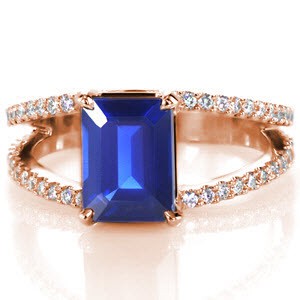 Clean lines and royal hues make Design 2506 an imperial piece. With a graduated split bead pave diamond band that has been created by hand from 14k white gold.  The split shank band guards a natural 1.80 emerald cut blue sapphire with four impressive prongs.