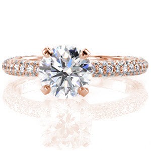 This ravishing design features a 1.50 carat round brilliant center stone which is elevated above the band in a traditional four prong setting. The center diamond is raised to allow a wedding band to sit flush next to this engagement ring. The band of this piece is luxuriously adorned with three rows of micro pavé.