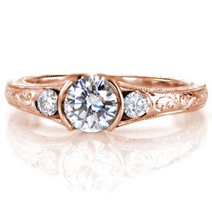 A beautiful design with a half-bezel set 0.75 carat round brilliant diamond fashioned on either side by a single side stone. The band is accented with splendid hand-formed platinum filigree curls and fascinating hand engraving. The edges have been textured with milgrain for a refined finish.