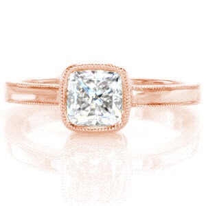 This 1.20 carat cushion cut diamond is surrounded by an elegant 14k yellow gold bezel setting. The band and bezel are outlined with milgrain detail to add a delicate texture and shape to the edges. The glow of the high polish band compliments the dazzling diamond center.