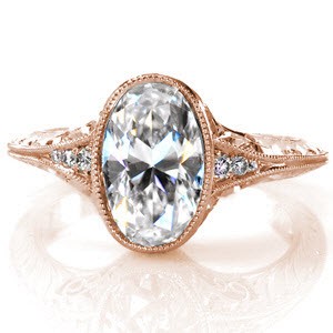 Unique rose gold vintage engagement ring in St. Louis. This gorgeous knife-edge band is antique inspired and detailed with hand engraving and hand formed filigree curls. The rose gold bezel setting for the oval center diamond really makes the diamond pop!