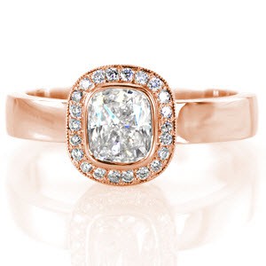 Crafted in 14k white gold, Design 2543 has a high polish streamlined band. The 1.00 carat cushion cut center diamond has a crisp full bezel which is surrounded by a halo of round cut diamonds and finished with hand applied milgrain on halo outer edge. This is a lustrous contemporary design.