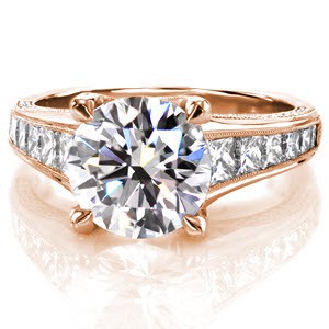 Malay features a 3.25 carat round center stone displayed in a crisscross trellis style four prong design with micro pavé diamond detail along the side. Filigree curls decorate the windows. Graduating princess cut diamonds gleam along the top of the ring, accented in a milgrain edge. 