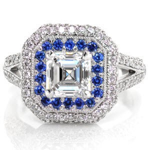 Design 2632 is a regal tribute to the Art Deco style. Taking center attention, a sparkling 1.00 carat asscher cut diamond surrounded by rich blue round cut sapphires. Reaching towards a halo with beveled corners is a split shank band and bezel set surprise diamonds, all set in 14k white gold.
