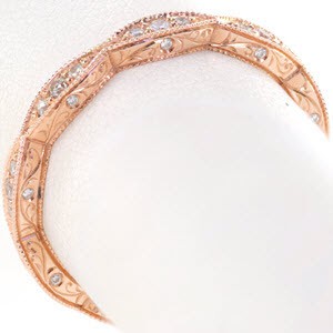 Rose gold wedding ring with marquise-shaped outline from top view and scroll hand engraving from the sides.