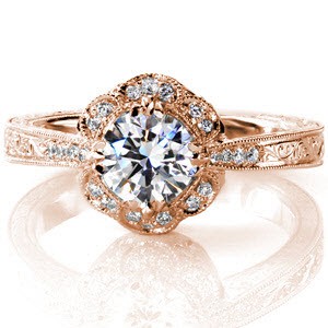 This lovely petal design features micro pavé diamonds set within the pattern. The 0.70 carat round center is held by vintage inspired claw prongs. The reverse taper shank delicately adjoins the crown. The piece is embellished with diamonds, hand engraving, milgrain edging and filigree detail.  
