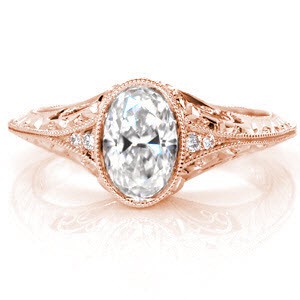 A reverse taper culminating in a knife edge band gives Design 2726 a distinct, vintage inspiration. The 0.75 carat oval cut center diamond is bezel set and flanked by two diamonds on either side. The band is further detailed with hand formed filigree and micro pavé diamonds embellishing the engraved patterns.  