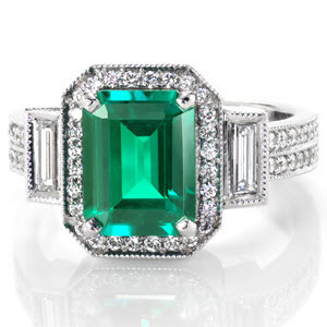 Linear facets of the emerald cut is mimicked in the straight rectangular baguettes that flank each side of the vivid emerald. Brilliantly faceted micro pavé diamonds outline the green gem adding a prism of colors when light strikes the stones. Similar size round diamonds from two rows along the band of the ring. 