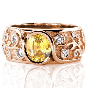 The edges of this interwoven design wrap up and around a bright yellow sapphire, cradling the cushion center in a bezel fashion. Relief engraving of the vines artistically spiral around the shape of a round brilliant diamond. The stipple background adds texture and contrasts the raised high polish engraving. 