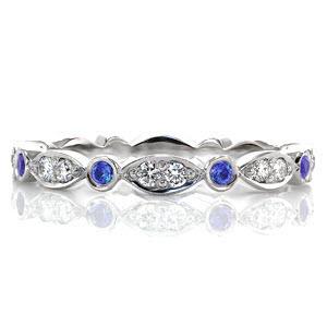Design 2823 is an eternity band crafted in 14k white gold. Alternating stations of round cut bezel set blue sapphires are accented by a marquise shape pattern with two bead set round brilliant diamonds. The high polish finish accents the vibrancy of the natural blue sapphires and white diamonds.