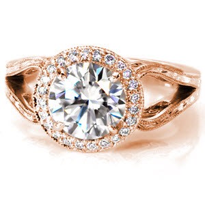 This regal design is breathtaking with a 1.50 carat round brilliant cut center diamond. The unique split-shank band ends in decorative loops as it reaches the micro pavé halo. The top of the band is covered with hand engraved designs, and the sides of the loop feature pockets of filigree. 