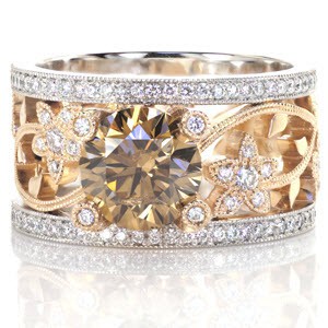 This custom two tone engagement ring is a real statement piece. The hints of yellow in the champagne colored center diamond are complimented by the 14k yellow gold vine and floral pattern. This organic design is framed on either edge by a 14k white gold band set with white diamonds.