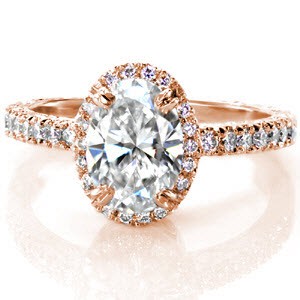 The 1.30 carat oval diamond is outlined in a halo of round brilliant diamonds for radiance and sparkle. The band is lavishly embellished with stones and a scroll pattern engraving. Hand formed filigree decorates the side of the halo for a picturesque view.  