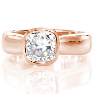 The Cashmere is a sleek, contemporary engagement ring with a wide tapered band. The 1.00 carat cushion cut center diamond is featured in a bezel setting on top of a woven trellis pattern visible from the sides of the piece. The luster of the high polished metal adds elegance to this beautiful ring.