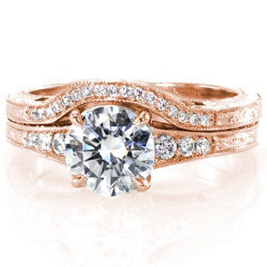 This delicate wedding band is the perfect pair for the Barcelona engagement ring. The width of the band matches engagement ring and curves out and around the flare of the center stone. The band is elegantly detailed with small diamonds, hand engraving on both outside surfaces, and hand forged filigree curls. 