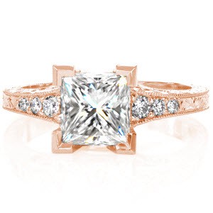 Design 2885 joins the vintage styling of engraving and hand crafted filigree with a stunning 1.50 carat Princess cut diamond. Chevron prongs create the most secure setting and the flared band is accented by graduated round cut diamonds. Hand applied milgrain and detailed under gallery add the perfect finishing touch.