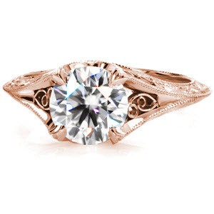 Crafted in Platinum, Design 2887 has a sparkling 1.25 carat round brilliant diamond secured by unique styled prongs. Hand formed filigree pairs with the flourishes of the relief hand engraved knife edge shank. Completing the design, hand applied milgrain has been added to the ring edges.