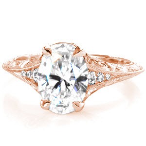 This antique inspired beauty showcases a brilliantly cut 2.00 carat oval in a 4 prong setting. Relief hand engraving, filigree scrolls and milgrain edges adorn the sides of the band for a vintage appeal. Round brilliant diamonds along the top of the band accentuates the brilliance of the platinum design.  