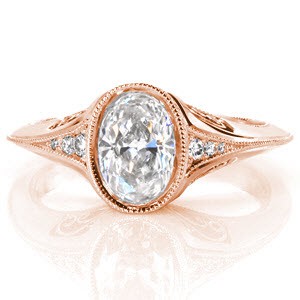 The smooth edges of this antique inspired design enhance the beauty of its artistic side view. The platinum filigree heightens its vintage appeal with the detail of each hand formed filigree scroll. Milgrain texture frames the edges and micro pavé diamonds adorn the top and sides of this unique oval setting. 