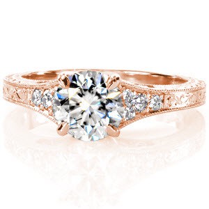 A brilliant 1.00 carat round center diamond is fashioned between a sleek four prong setting. The flared hand engraved band is embellished with diamonds adding sparkle and shine to this antique inspired design. The hand wrought filigree curls enhance its vintage appeal.  